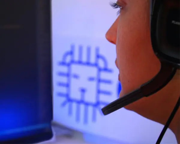 Empleada de Aslam mirando un ordenador con código y unos cascos puestos